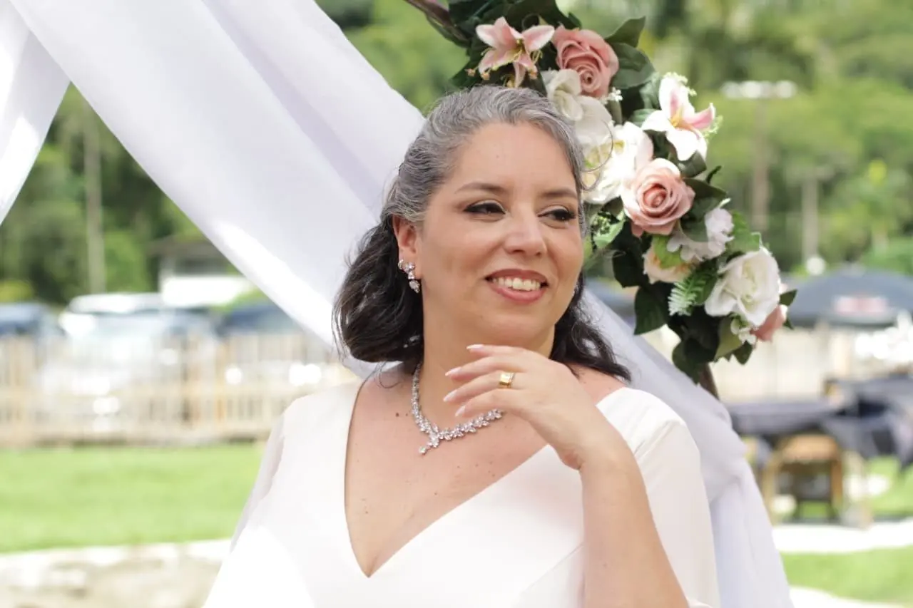 Noiva sorrindo com buquê de flores durante casamento no Rancho Santa Inês